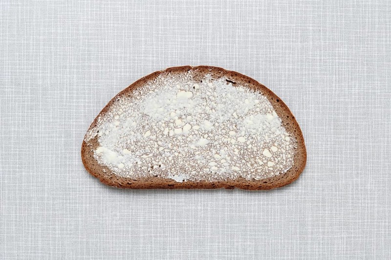 Top shot of a slice of bread smeared with margarine on a white Resopal plate