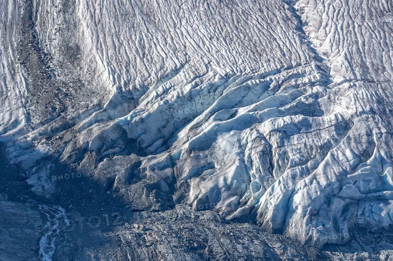 Intricate patterns of ice and rock are showcased in this stunning glacial landscape, revealing the effects of time on the frozen surface. The bright daylight emphasises the textures and colours. Gorner Glacier, Zermatt, Valais, Alps, Swiss