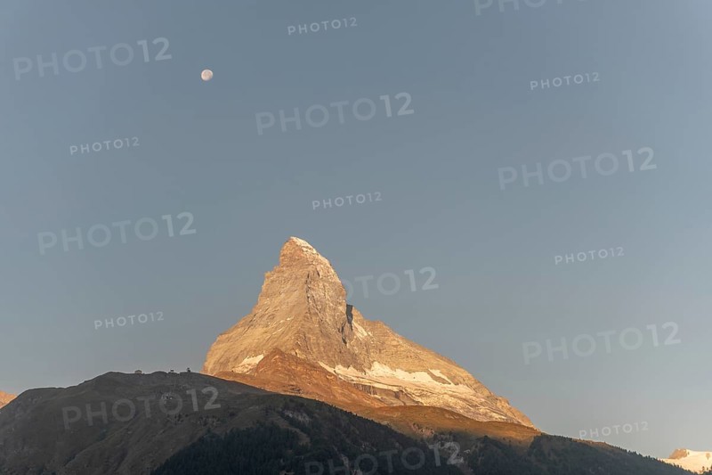 The iconic Matterhorn stands high above a clear evening sky illuminated by a bright moon. This breathtaking view captures the beauty and serenity of the Swiss Alps near Zermatt. Valais, Alps, Switzerland