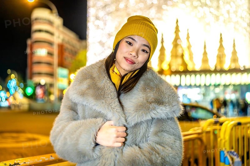 Fashionable young woman wearing winter clothes enjoying christmas night lights in the city