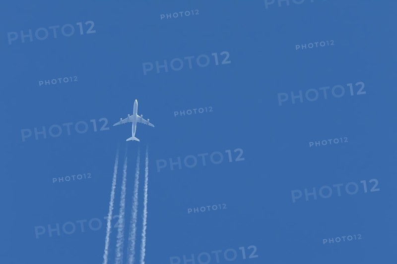 Airbus A340-300 jet aircraft of Lufthansa airlines in flight in a blue sky with vapour trails or contrails behind, England, United Kingdom