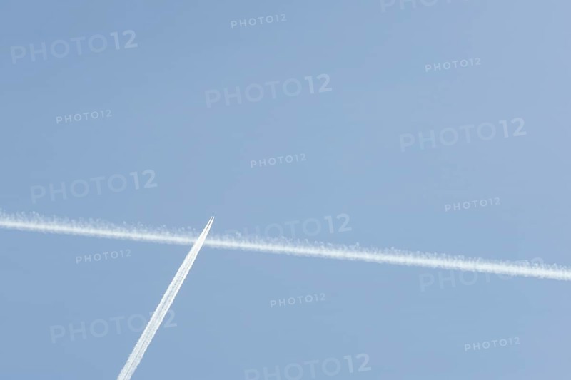 Jet passenger aircraft with a vapour trail or contrail flying in a blue sky, England, United Kingdom