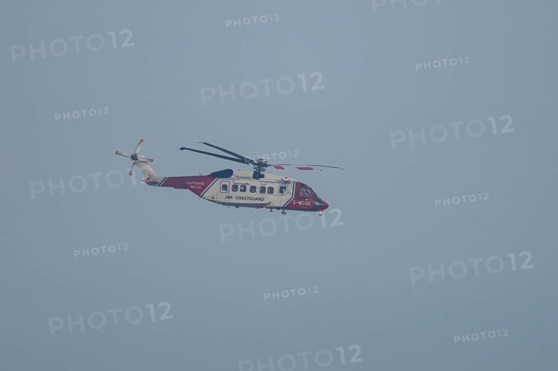 Sikorsky S-92A helicopter of the UK HM Coastguard flying in a blue sky, England, United Kingdom