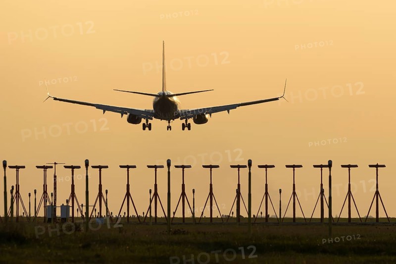 Boeing 737 jet passenger aircraft of Ryanair airlines landing over runway lights at sunset, London Stansted airport, Essex, England, United Kingdom