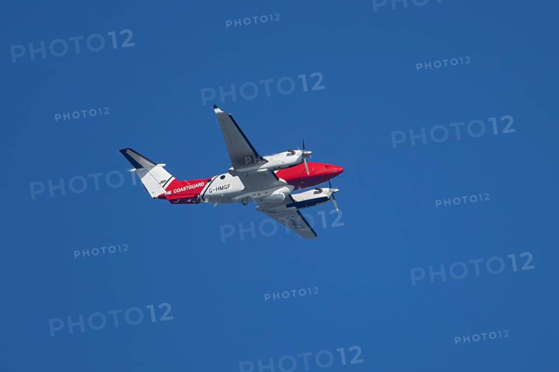Beech King Air 350 light aircraft of the UK HM Coastguard flying in a blue sky, England, United Kingdom