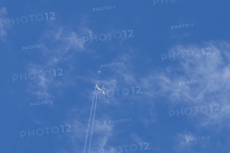 Two airliners Airbus A380 jet passenger aircraft of Emirates airlines and a Boeing 737 of Norweign Air flying in a blue sky, England, United Kingdom