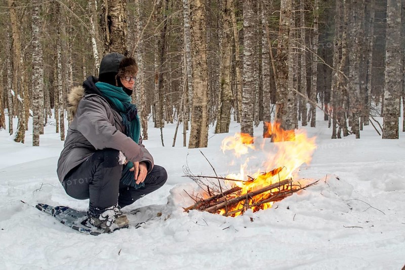 A woman warms herself by a campfire in winter, Gaspesie national park, Province of Quebec, Canada, north America