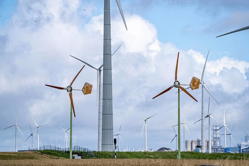 Mini wind turbines, from the Dutch company Ecoways EAZ wind turbine, produces up to 15 kW power and up to 45, 000 KW electricity per year, for self-consumption, intended primarily for farms, rotors made of wood, from forests in the Netherlands, easy to recycle, quick and easy to set up, for cheap power supply in the countryside, behind it large wind turbines of a wind farm near Eemshaven, Netherlands