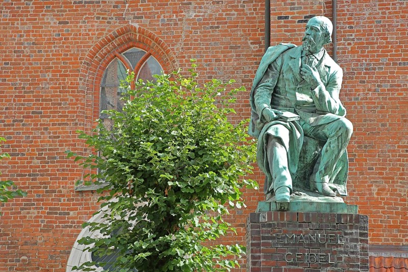 Monument to the writer and poet Emanuel Geibel by Hermann Volz 1889, seated, inscription, bronze sculpture, Grünspan, Geibelplatz, Old Town, Lübeck, Schleswig-Holstein, Germany