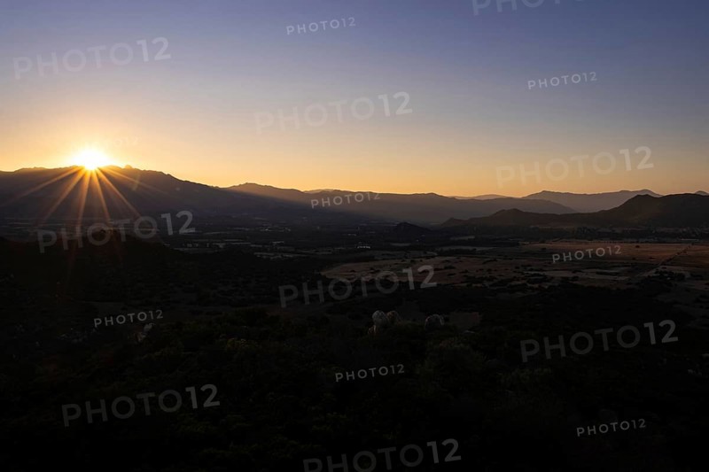 The sun sets behind the mountains on the Mediterranean island of Sardinia, Monte Nai, Costa Rei, Sardinia, Italy