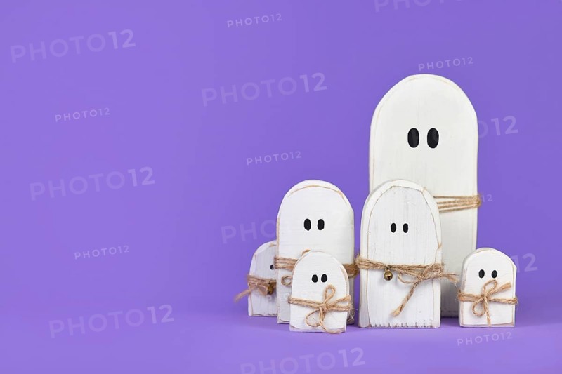 Cute wooden white Halloween ghost ornaments on purple background