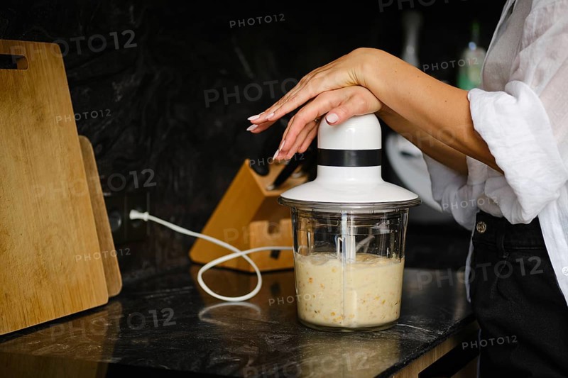 Close-up view of blending ripe bananas and sea buckthorn berries in a stylish kitchen. The focus is on the blender as the healthy ingredients mix together