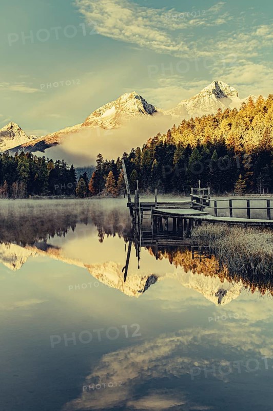 Lake Staz near Sankt Moritz in the Engadin in Switzerland. Morning atmosphere with fog in autumn. Water reflection and snow-covered mountains in the background