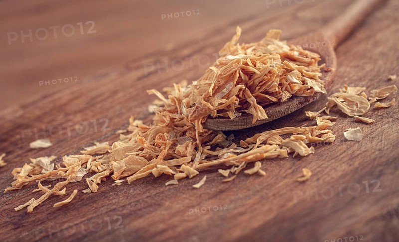 Smoked onion flakes, on a wooden spoon, wooden table, close-up