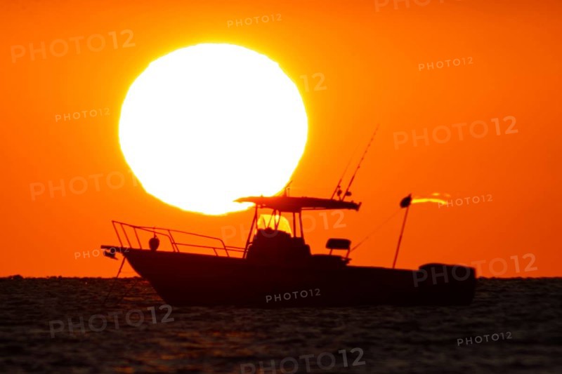 The sun rises behind a boat on the Costa Rei, a coastal stretch of the Italian Mediterranean island of Sardinia, Monte Nai, Costa Rei, Sardinia, Italy
