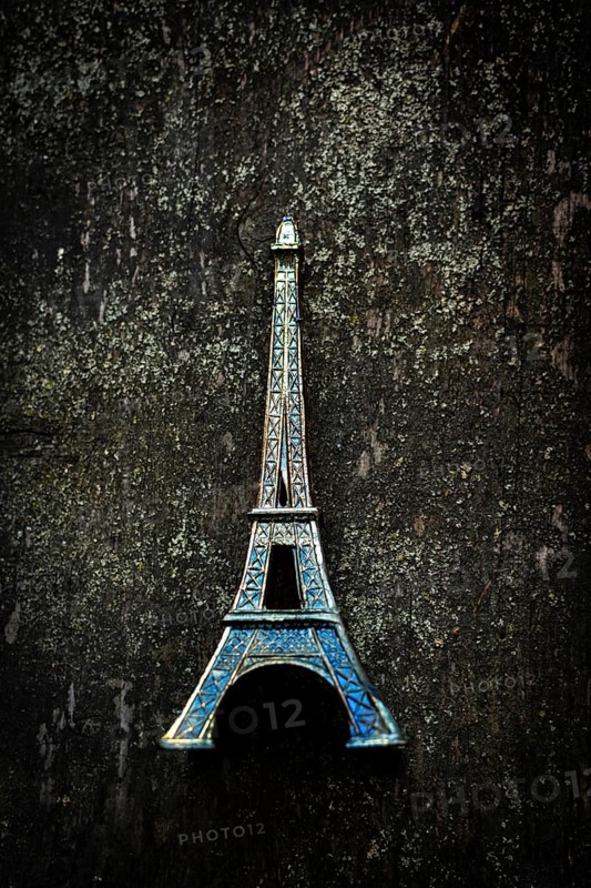 Vibrant blue Eiffel Tower keychain highlights detailed craftsmanship as it stands out against a textured dark surface, creating a striking visual contrast that captures attention
