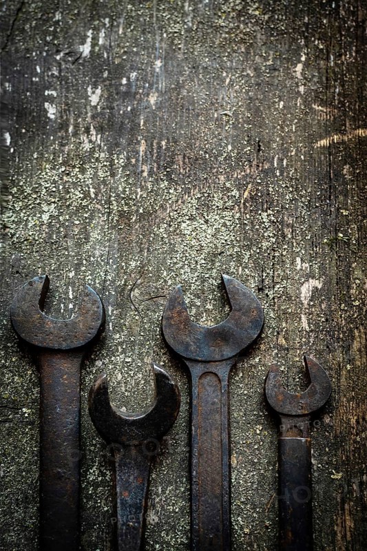 Different sizes of wrenches are arranged neatly on a weathered wooden surface, showcasing their craftsmanship and unique shapes perfect for mechanical tasks or repairs