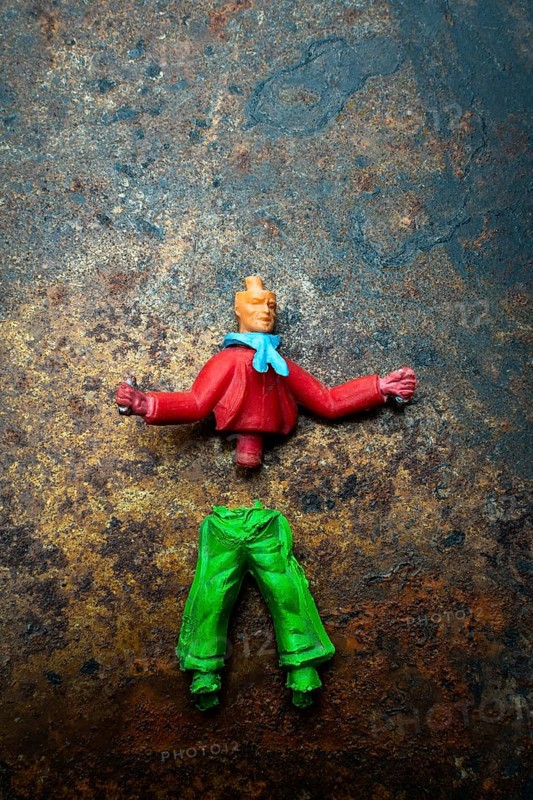 Brightly colored toy figure parts lie scattered on a rusted metal surface, showcasing a mix of red and green pieces, suggesting an ongoing toy repair or customization effort