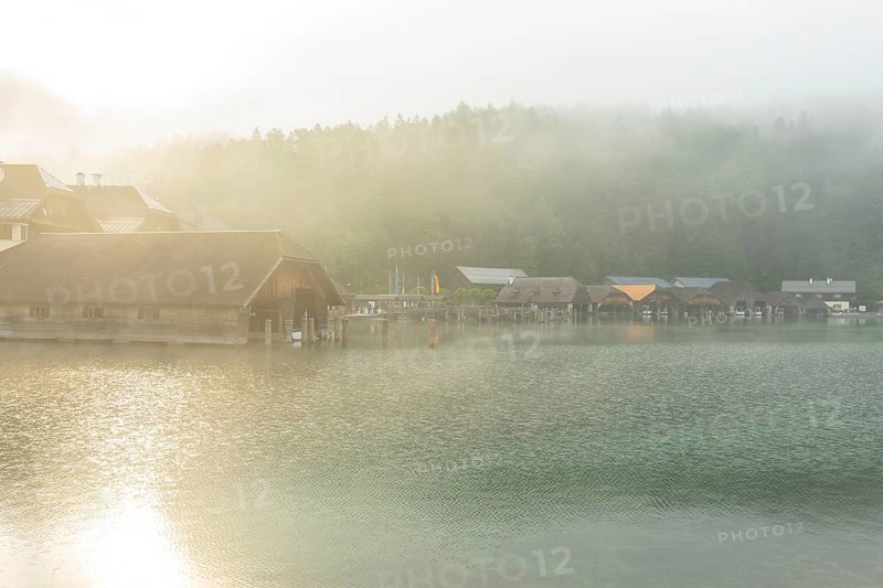 Mystical morning at Königssee in Schönau with boathouses. Sunrise and beautiful wafts of mist over the Königssee in the basin