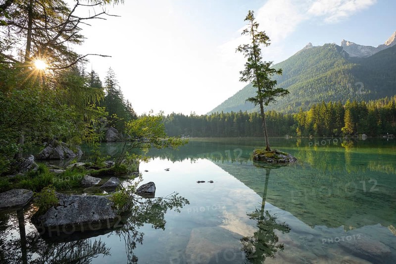 Summer morning at Hintersee near Ramsau in Berchtesgadener Land with sun star and reflection