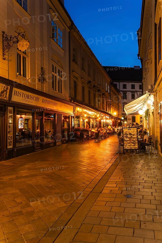 Cosy alley in the old town with illuminated cafés and historic pastry shop in Bratislava, Slovakia