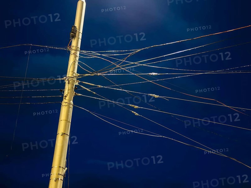 Night shot of many cables and wires for overhead lines on a lamppost in Bratislava, Slovakia