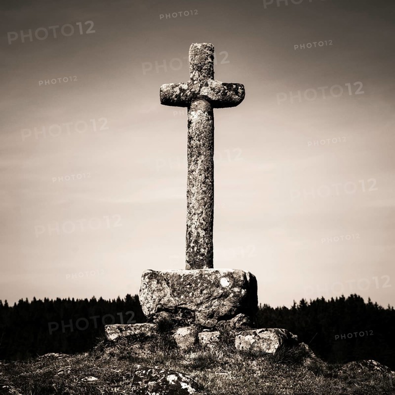 In the heart of Auvergne, a weathered stone cross rises majestically against a backdrop of untouched nature. Its presence reflects the region's rich history and spiritual heritage. Puy de Dome. Auvergne Rhone Alpes. France