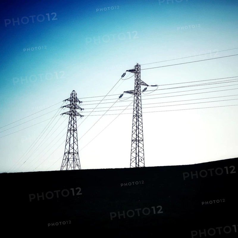Two power towers reach upwards, silhouetted against a transitioning twilight sky. The horizon is gently rolling, creating a peaceful atmosphere during dusk