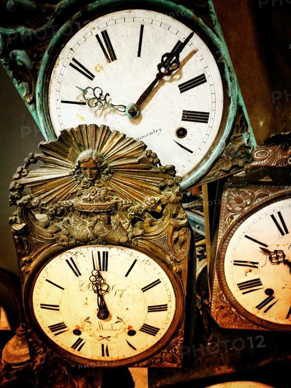 A collection of vintage clocks showcasing ornate craftsmanship and classic styling. Each clock features Roman numerals and unique decorative elements, highlighting their historical significance