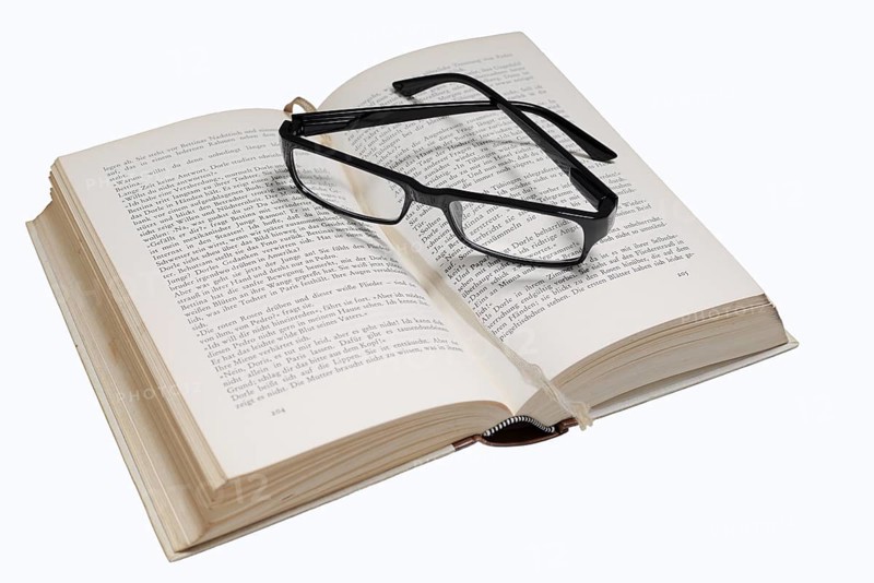 Reading glasses and book on a white background