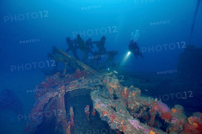 A diver explores a rusty shipwreck on the seabed. Dive site wreck Ville de Grasse, Giens peninsula, Mediterranean Sea, Provence Alpes Côte d'Azur, France