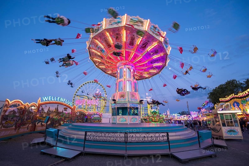 Luminous carousel turns on a colourful funfair, chain carousel, spring festival, Cannstatter Wellenflug, illuminated, blue hour, Cannstatter Wasen, Bad Cannstatt, Stuttgart, Baden-Württemberg, Germany