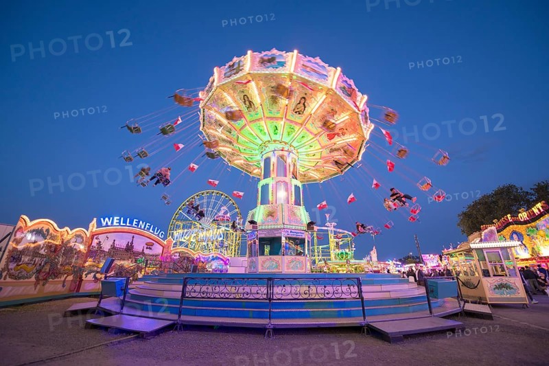 A chain carousel with lights turns at a fairground at dusk, chain carousel, spring festival, Cannstatter Wellenflug, illuminated, blue hour, Cannstatter Wasen, Bad Cannstatt, Stuttgart, Baden-Württemberg, Germany