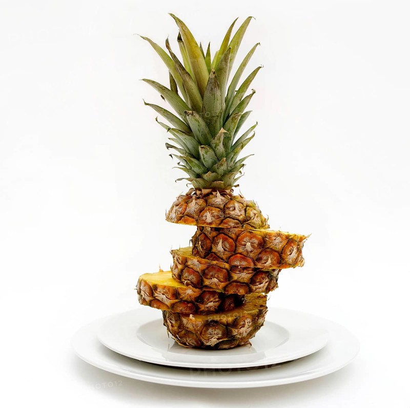 A carefully sliced pineapple is presented on white plates, highlighting its textured layers and vibrant color against a minimalistic backdrop, capturing a fresh fruit experience in France