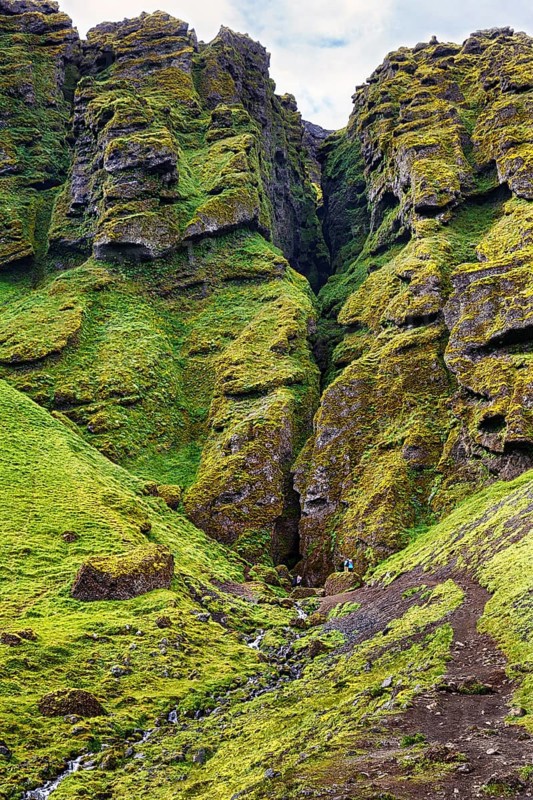 Moss-covered rock formation with entrance to the mystical lava cave, Sönghellir lava tube, Cave of Songs, Arnarstapi, Snaefellsjökull National Park, Snaefellsnes Peninsula, West Iceland, Iceland