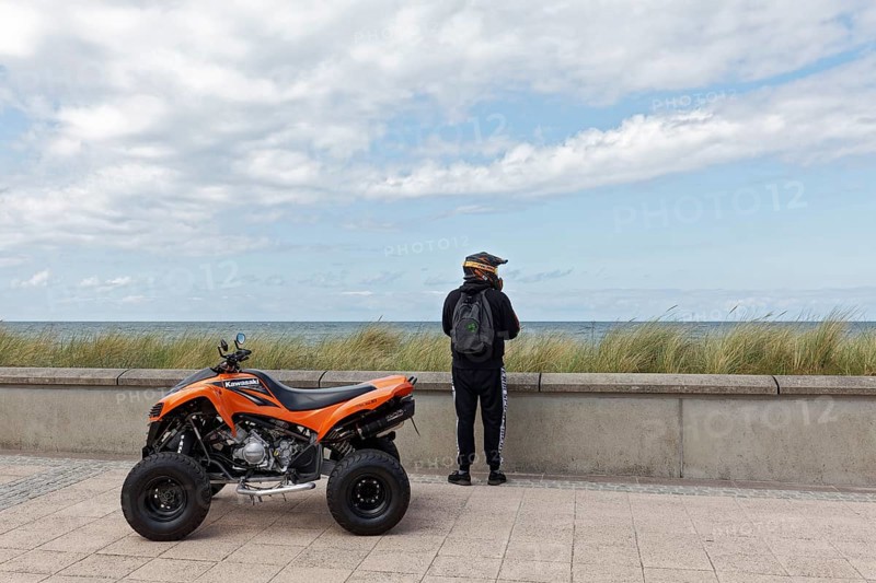 Motorcyclist with Kawasaki Quad Bike on the beach promenade, looking at the sea, Baltic resort Kühlungsborn, Baltic Sea, Mecklenburg-Vorpommern, Germany