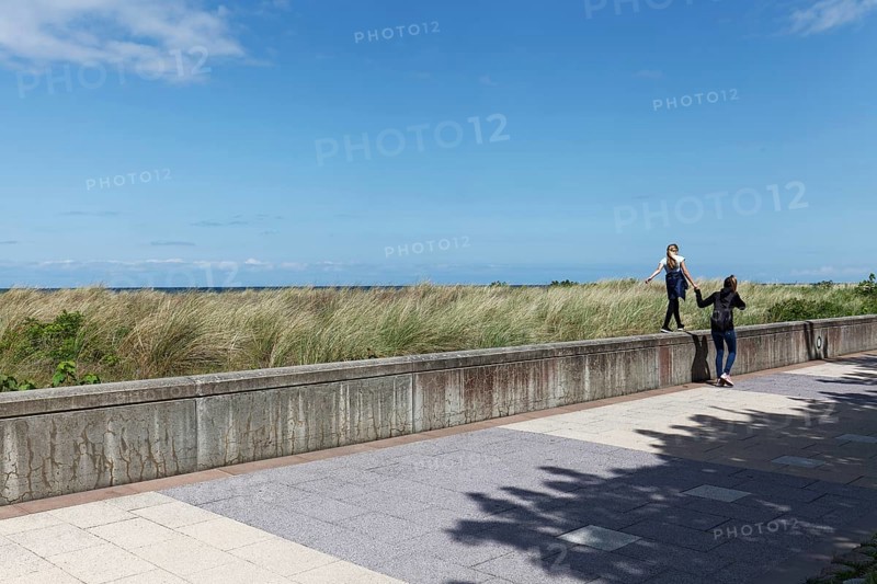 Teenager leads little girl by the hand over a wall on the beach promenade, Baltic resort Kühlungsborn, Baltic Sea, Mecklenburg-Western Pomerania, Germany