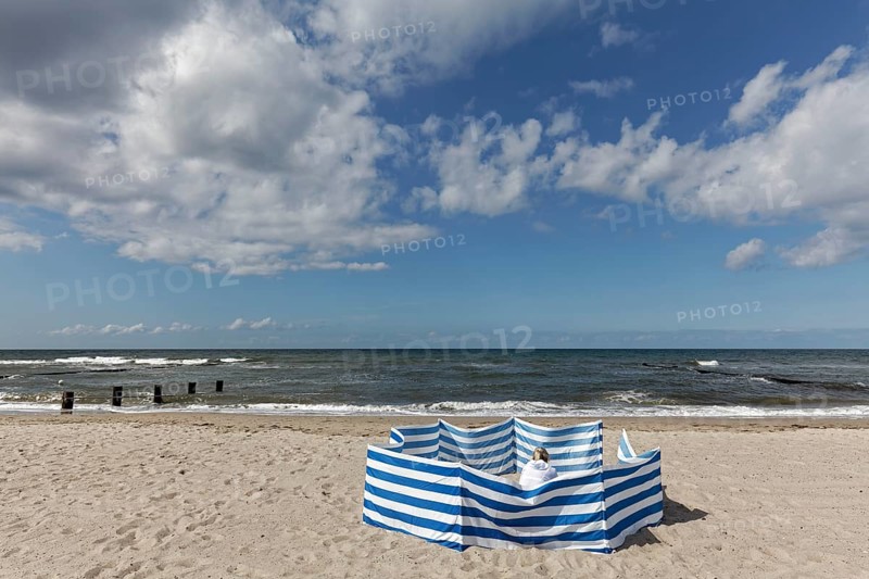 Deserted beach with person behind windbreak, blue sky, Baltic Sea near Kühlungsborn, Mecklenburg-Western Pomerania, Germany