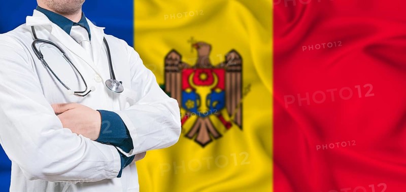 Moldova healthcare concept. Male doctor on Moldova flag. Doctor with crossed arms on Moldova flag