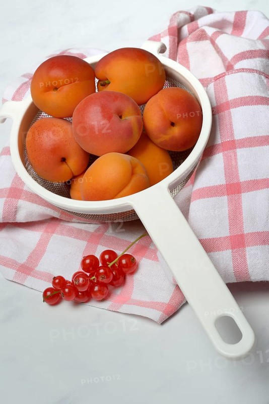 Apricots in a colander and redcurrants