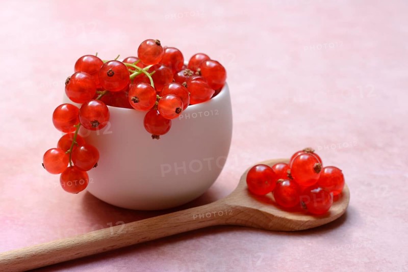 Redcurrants in small bowls and wooden spoon, Ribes rubrum