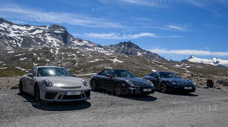 Three Porsche 911 sports cars parked on an Alpine road above the tree line, 911 991 GT3 on the left, 911 997 Carrera 4s in the centre, 911 992 Carrera 4s on the right, Col de l'Iseran pass, departmental road D902, Route des Grandes Alpes, Département Savoie, Auvergne-Rhône-Alpes region, Graian Alps, France