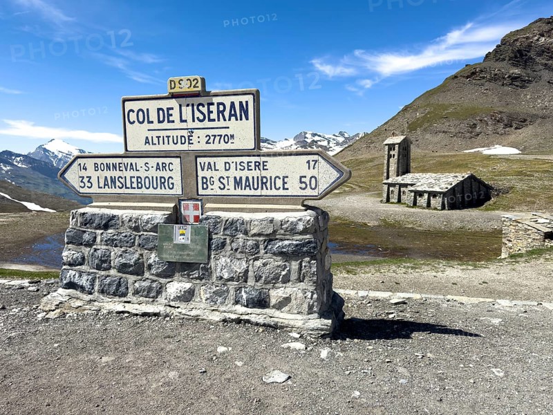 In the foreground signpost to the pass summit of the highest navigable alpine pass Col de l'Iseran 2764 2770 metres high, Iseran Pass, Iseran, below direction signs to Lanslebourg and Bourg Saint Maurice, in the background chapel Chapelle Notre-Dame-de-Toute-Prudence, Col de l'Iseran, departmental road D902, Route des Grandes Alpes, Département Savoie, Region Auvergne-Rhône-Alpes, Graian Alps, France
