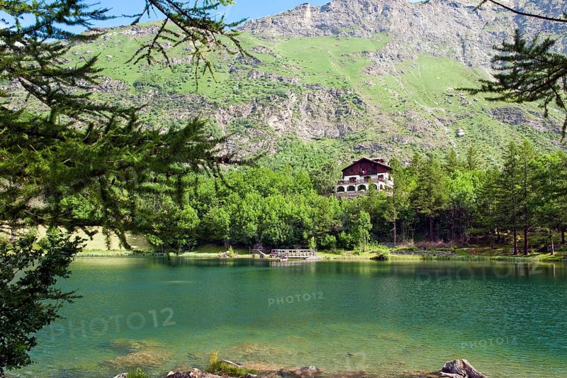 View of mountain lake Lago Grande near Moncenisio in Val Cenischia in the Graian Alps, behind it chalet on the lake, Moncenisio, Piedmont, Italy