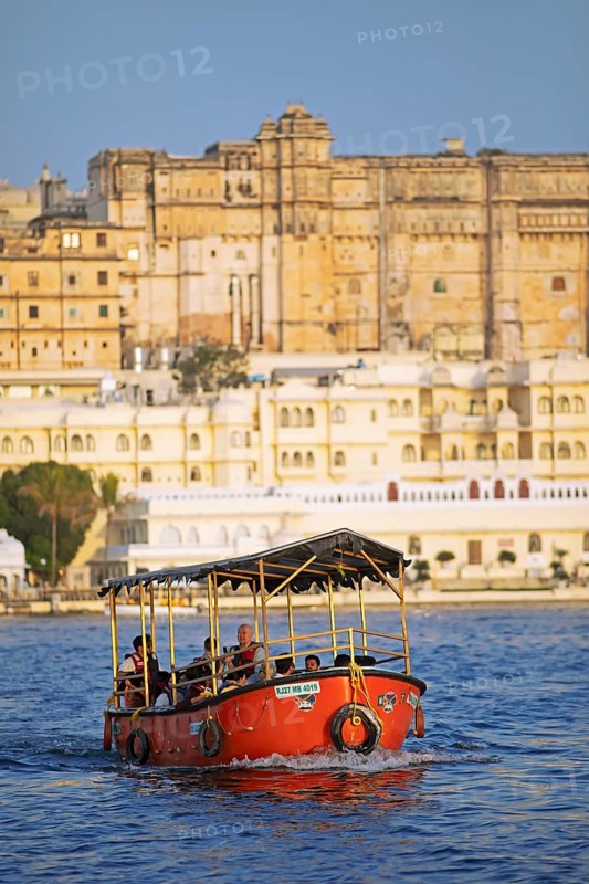 Electric excursion boat on Lake Pichola, behind the City Palace in the evening light, Udaipur, Rajasthan, India