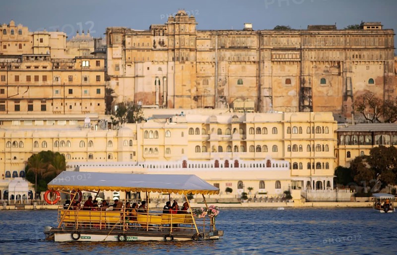 Electric excursion boat on Lake Pichola, behind the City Palace in the evening light, Udaipur, Rajasthan, India
