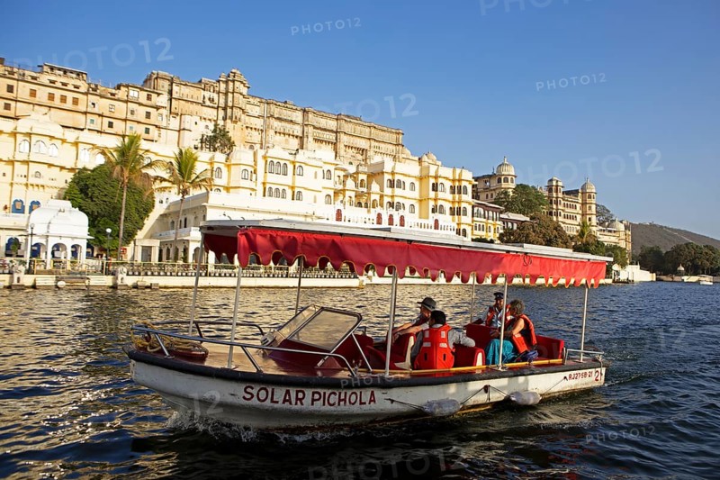 Excursion boat on Lake Pichola, behind the City Palace in the evening light, Udaipur, Rajasthan, India