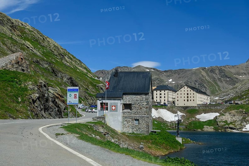 View of historic Swiss border building in the foreground Former passport control checkpoint Passport control Border control Customs control Customs at road crossing National border State border between Italy and Switzerland, on the left next to it sign for road users about toll sticker, on the right Lac du Grand St-Bernard, in the background historic building hostel Auberge de l'Hospice at the top of the Great Saint Bernard Pass, Colle del Gran San Bernardo, Col du Grand Saint Bernard, Italy, Switzerland