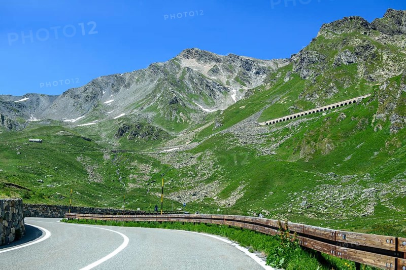 View of front curves of pass road mountain road alpine road above tree line, in the centre right in the background gallery above carriageway road as protection against falling rocks on southern ascent descent south ramp of to alpine pass Great Saint Bernard Pass, Colle del Gran San Bernardo, Col du Grand Saint Bernard, Valle d'Aosta, Italy