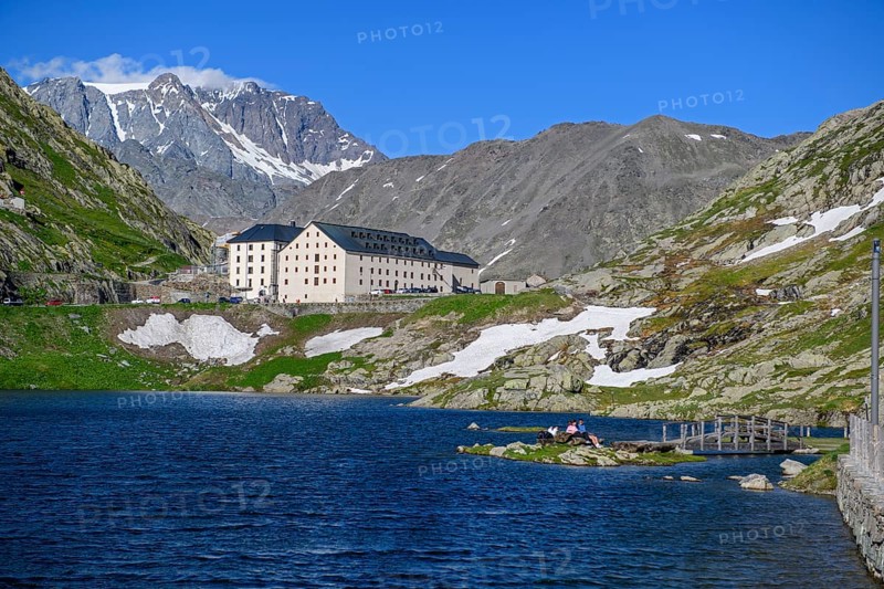 View from Italian side on small island in Lac du Grand Saint Bernard in the background on Swiss territory historic Auberge Herberge Hospice on pass summit of 2473 metres high alpine pass Great Saint Bernard, Saint-Rhémy-en-Bosses, region Valle d'Aosta, Italy